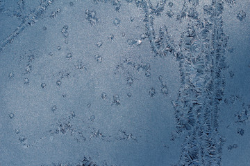 Crystal ice condensation patterns on a frosty glass window pane