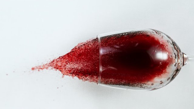 Super Slow Motion Top Shot of Falling Glass with Red Wine on White Cloth at 1000fps.