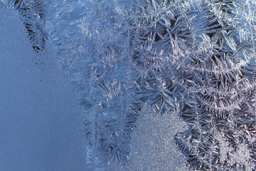 Crystal ice condensation patterns on a frosty glass window pane