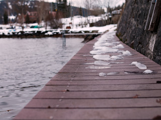 Obraz premium Light snow on a wooden dock at the Lake Joux or Lac de Joux in Switzerland.