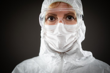 Female Medical Worker Wearing Protective Face Mask and Gear Against Dark Background