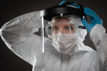 Female Medical Worker Wearing Protective Face Mask and Gear Against Dark Background
