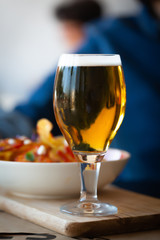 Glass of beer and chips on wooden table