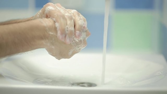 Closeup of man washing hands in slow motion - zoom in