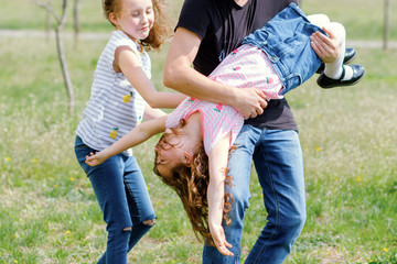 Dad and two daughters play active games outdoor. father is messing with girls. man raised a...