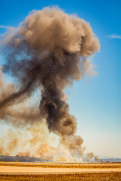 Vertical image of column of smoke from ground up with tornado visible from munitions explosion