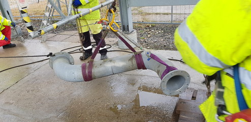 riggers move the pipe using two chain blocks