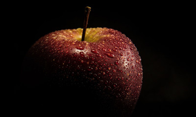 red apple with drops of water on black background