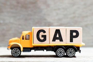 Truck hold letter block in word GAP (abbreviation of good agricultural practice) on wood background