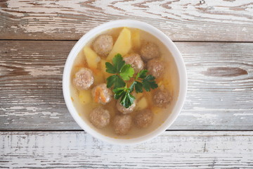 Vegetable soup with meatballs and potatoes on a white rustic table