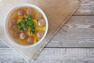 Vegetable soup with meatballs and potatoes on a white rustic table