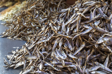 Mountains of small dry stockfish are sold on a street tray. Close-up