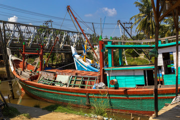 Fototapeta na wymiar Old wooden fishing boats stand in a small port of southeast asia