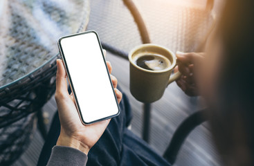 Mockup image blank white screen cell phone.woman hand holding texting using mobile on desk at coffee shop.background empty space for advertise text.people contact marketing business,technology