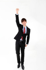 Young smart handsome Asian man business office wearing suit tie on white background look at camera walk forward fist up joy success
