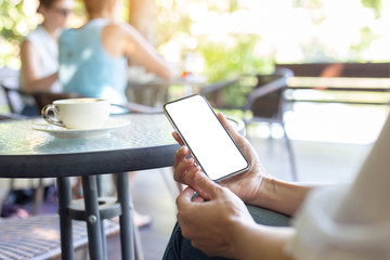 Mockup image blank white screen cell phone.woman hand holding texting using mobile on desk at coffee shop.background empty space for advertise text.people contact marketing business,technology
