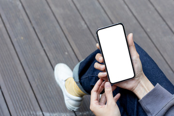 Mockup image blank white screen cell phone.woman hand holding texting using mobile sitting at outdoor.background empty space for advertise text.people contact marketing business,technology