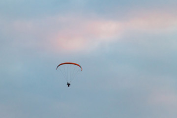 Powered paragliding, man flying high in a sky with parachute and engine on his back