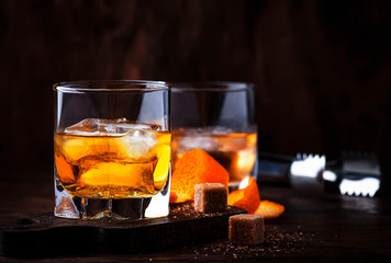 Alcoholic old fashioned cocktail with orange slice, cherry and orange peel garnish