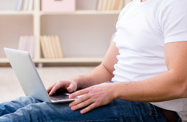 Fototapeta premium Man working on laptop at home on carpet floor