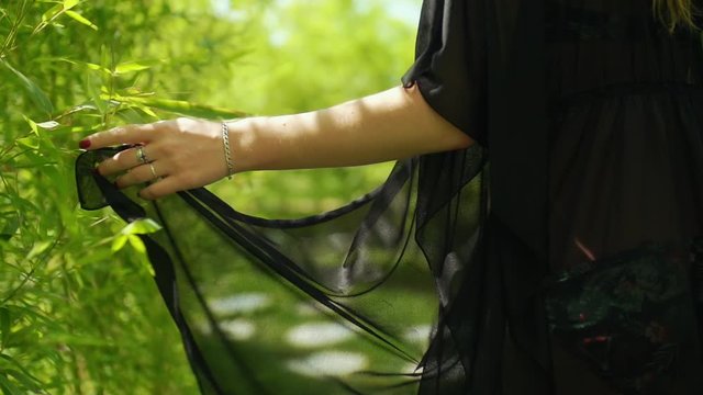 young girl is walking among greenery with bikini and pareo.