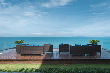 Long wooden sofa chair on the deck with tropical ocean at the background in a resort