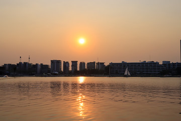 Obraz premium CItyscape modern apartment building near a lake under sunset twilight with cloud sky background with water reflections for background.
