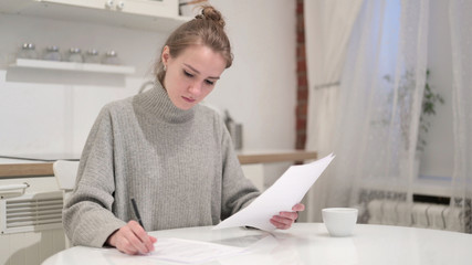 Focused Young Woman Writing on Paper at Home