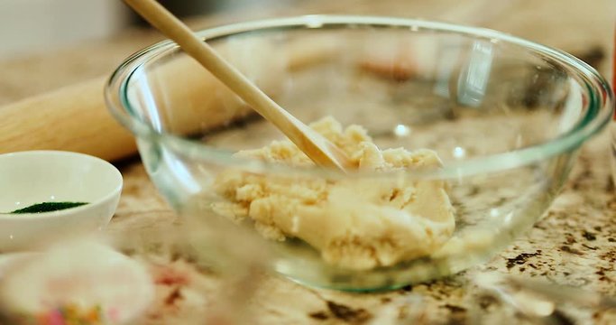 Cookie dough and baking mix for cookies or a desert pastery. Sprinkles and decorations sit aside a large glass bowl with a wooden spoon and mix. slow motion 4k