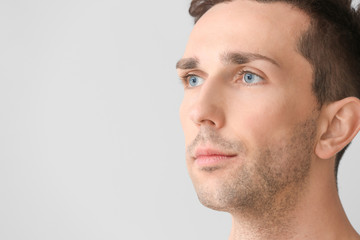 Fototapeta premium Handsome young man on light background. Plastic surgery concept