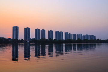 Obraz premium CItyscape modern apartment building near a lake under sunset twilight with cloud sky background with water reflections for background.