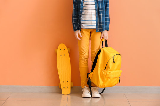 Cute Little Boy With Skate And Backpack Near Color Wall