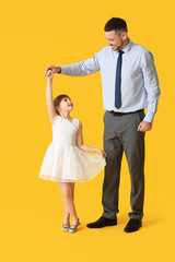 Father and his little daughter dancing against color background