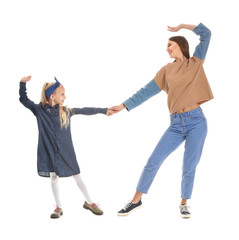 Fototapeta premium Woman and her little daughter dancing against white background