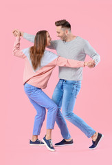 Happy couple dancing against color background