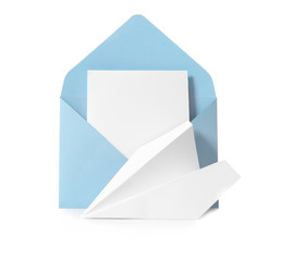 Envelope with card and paper airplane on white background