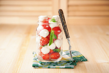 Salad Caprese in a glass jar on a table. Selective focus. Copy space.
