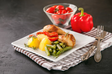 the baked chicken legs with vegetables in a plate on a table, selective focus, copy space