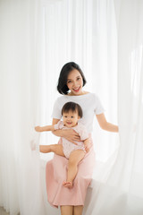 Young mother holding a baby standing in a tulle