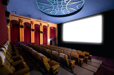 Cinema theater screen in front of seat rows in movie theater showing white screen projected from cinematograph. The cinema theater is decorated in classical style for luxury feeling of movie watching. - obrazy, fototapety, plakaty