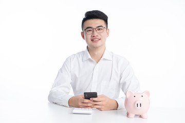 A young Asian man is using his mobile phone and laptop