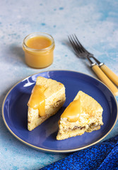 Plate with two pieces of pumpkin cheesecake and with caramel topping on a blue ceramic plate, light blue stone background. Selective focus. 