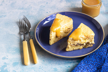 Plate with two pieces of pumpkin cheesecake and with caramel topping on a blue ceramic plate, light blue stone background. Selective focus. 