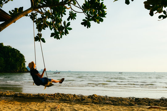 single girl play on a swing on Ao Nang beach, Krabi, Thailand. - Powered by Adobe