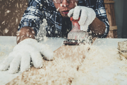 Carpenter working on wood craft at workshop to produce construction material or wooden furniture. The young Asian carpenter use professional tools for crafting. DIY maker and carpentry work concept.