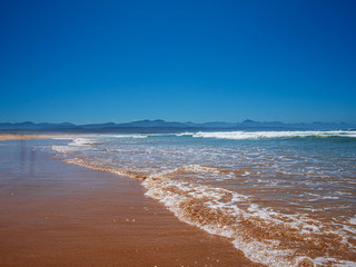 Africa Plettenberg Bay Ocean Beach with mountain scene at background