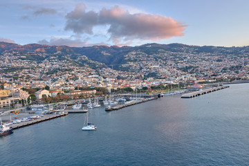 Fototapeta na wymiar Scenic view of Funchal - capital of Portugal's Autonomous Region of Madeira. Beautiful summer sunny look of small town on hills on paradise tropical island in Atlantic ocean.