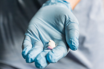 doctor holding medical drugs, pills. hands in blue latex gloves.