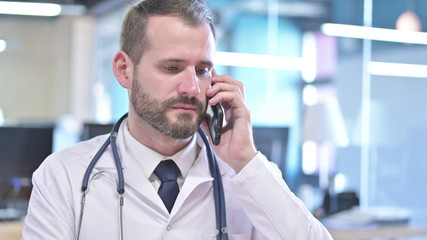 The Portrait of Young Doctor talking on Smartphone in Office