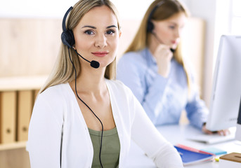 Portrait of call center operator at work. Group of people in a headset ready to help customers....